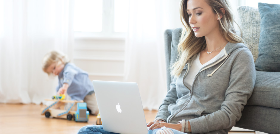 Mom working on laptop while child is playing with truck