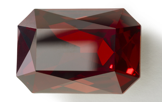 Close up of red crystal with precisely cut facets. 