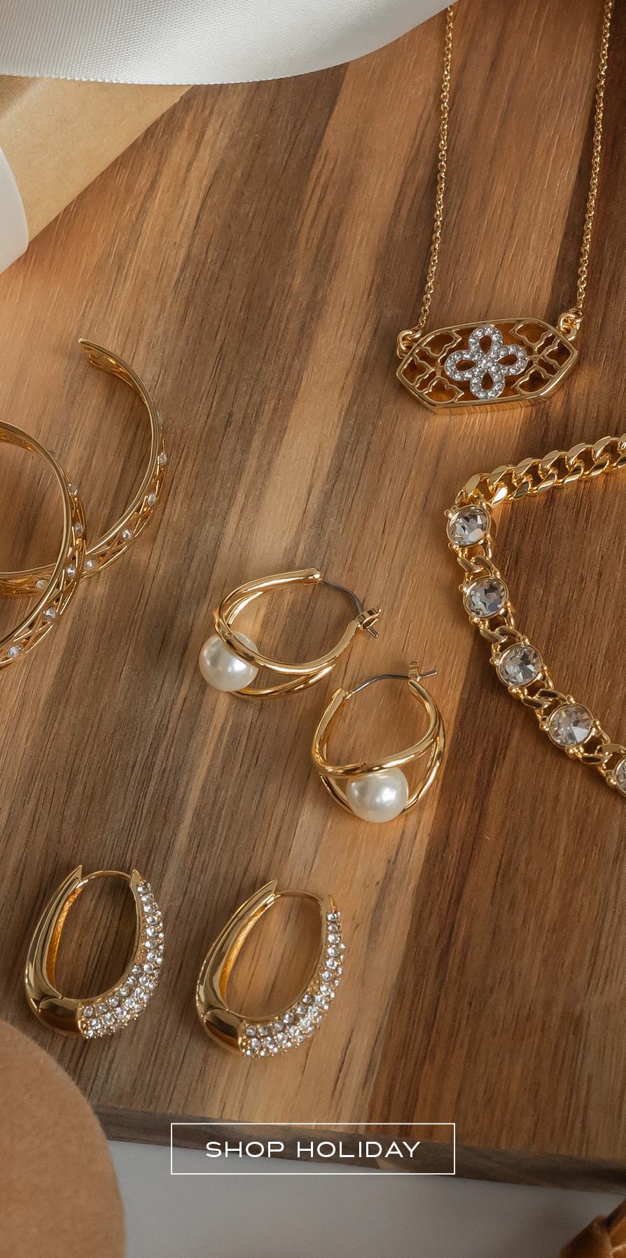Flatlay of golden jewelry with pearls and crystal